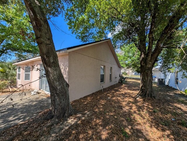 view of side of property with central air condition unit and stucco siding