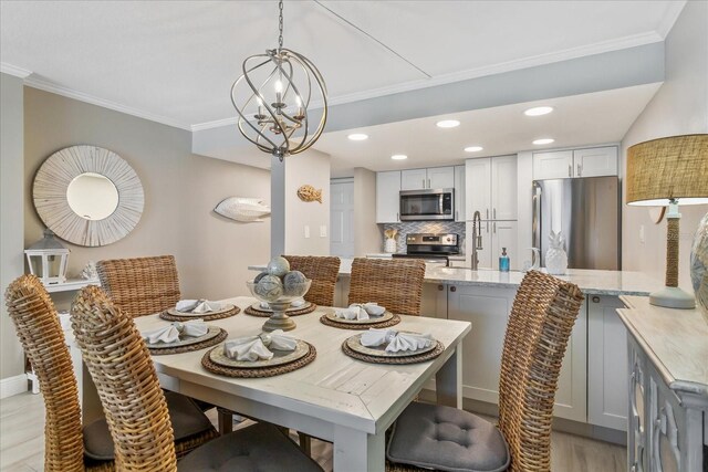 dining room featuring a notable chandelier, ornamental molding, recessed lighting, light wood-style floors, and baseboards