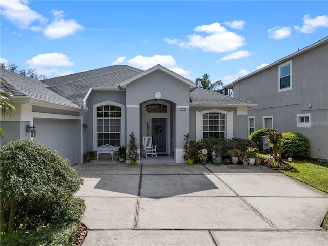 view of front of home with a garage, driveway, a shingled roof, and stucco siding