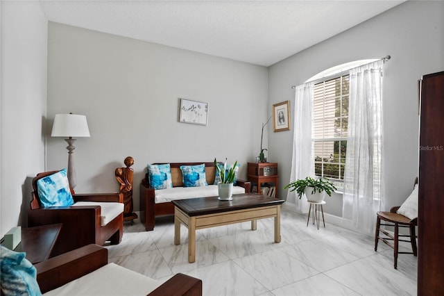 living area featuring marble finish floor and a textured ceiling