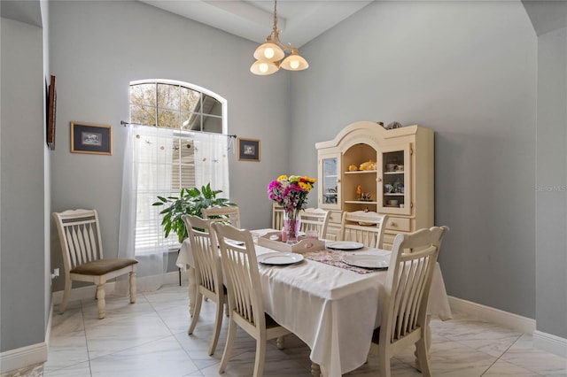 dining area with marble finish floor, a high ceiling, and baseboards