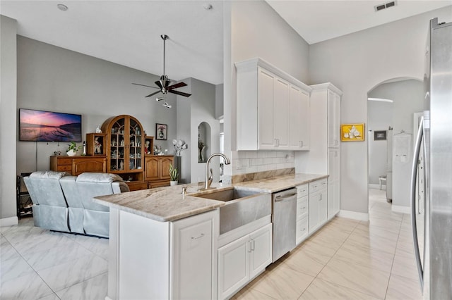 kitchen with arched walkways, marble finish floor, a sink, and stainless steel dishwasher