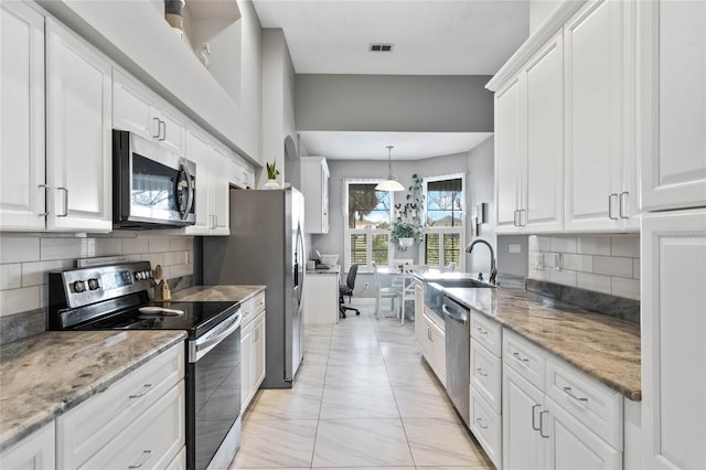 kitchen with stainless steel appliances, white cabinetry, visible vents, and light stone counters