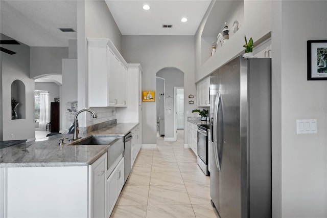 kitchen featuring visible vents, light stone counters, stainless steel appliances, white cabinetry, and a sink