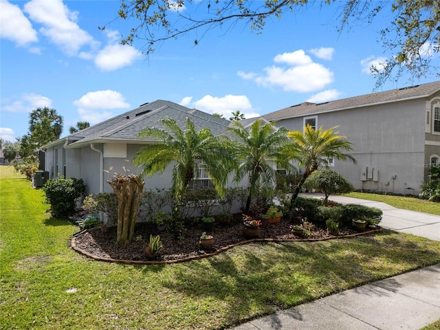 view of home's exterior with a shingled roof, central AC unit, concrete driveway, a yard, and stucco siding