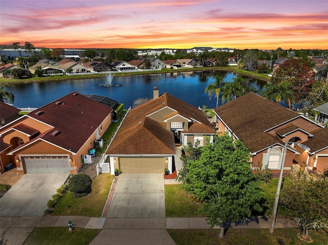 view of front facade featuring a residential view, an attached garage, driveway, and a water view