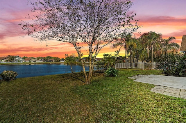 view of yard featuring a water view, a patio, and fence