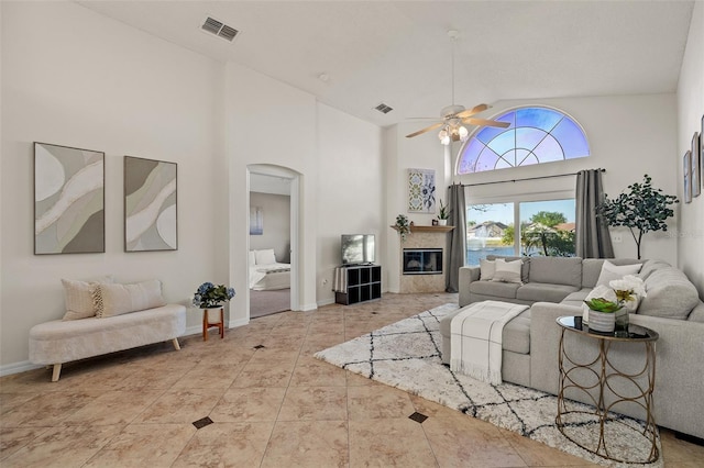 tiled living room with high vaulted ceiling, a ceiling fan, visible vents, and arched walkways