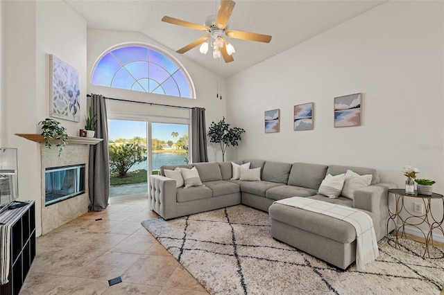 living area featuring high vaulted ceiling, light tile patterned flooring, a high end fireplace, ceiling fan, and a water view