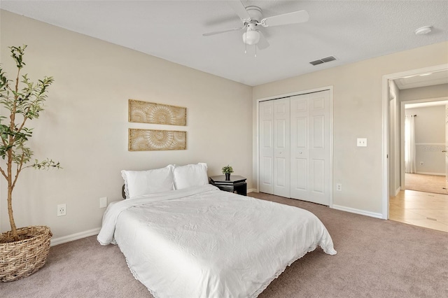 carpeted bedroom with visible vents, baseboards, a closet, and a ceiling fan