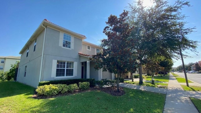 view of front of home with a front yard, a garage, driveway, and stucco siding