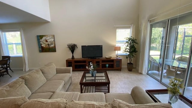 living area featuring light tile patterned floors, a healthy amount of sunlight, and a towering ceiling