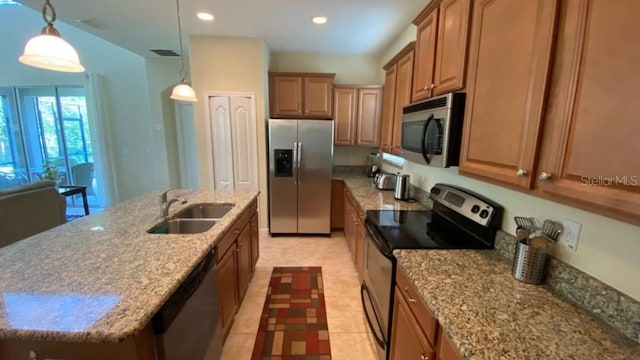 kitchen featuring visible vents, a sink, brown cabinets, stainless steel appliances, and a kitchen island with sink