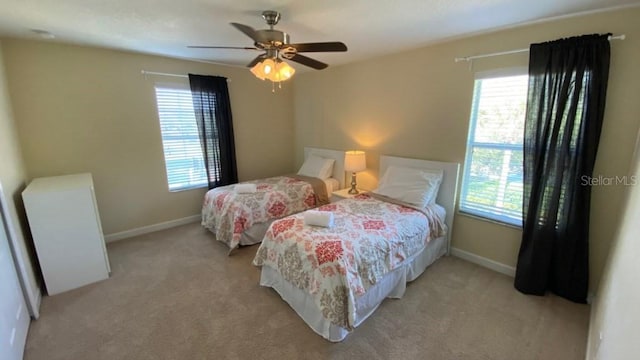 bedroom with multiple windows, light colored carpet, and baseboards