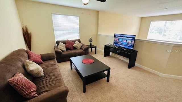 living room with baseboards, light colored carpet, and a ceiling fan