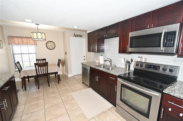 kitchen featuring a sink, decorative light fixtures, backsplash, stainless steel appliances, and light tile patterned floors