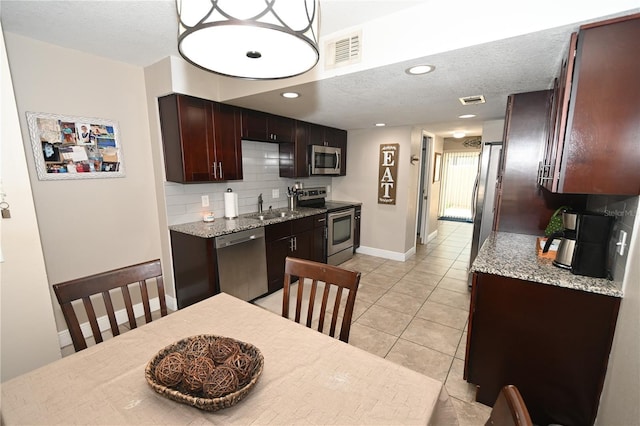 kitchen featuring visible vents, light tile patterned flooring, stainless steel appliances, decorative backsplash, and a textured ceiling