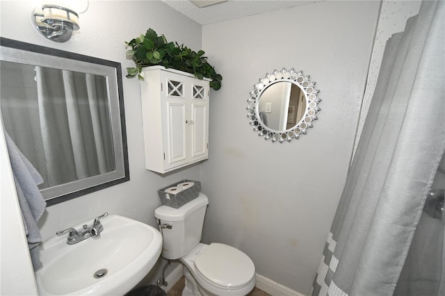 bathroom with a sink, baseboards, and toilet