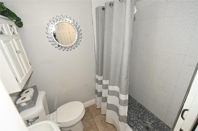 full bathroom with baseboards, toilet, tile patterned flooring, and a tile shower