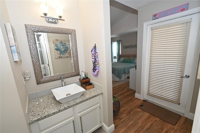 bathroom with connected bathroom, baseboards, wood finished floors, and vanity