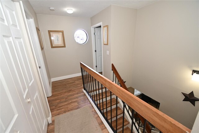 hall featuring baseboards, an upstairs landing, and wood finished floors