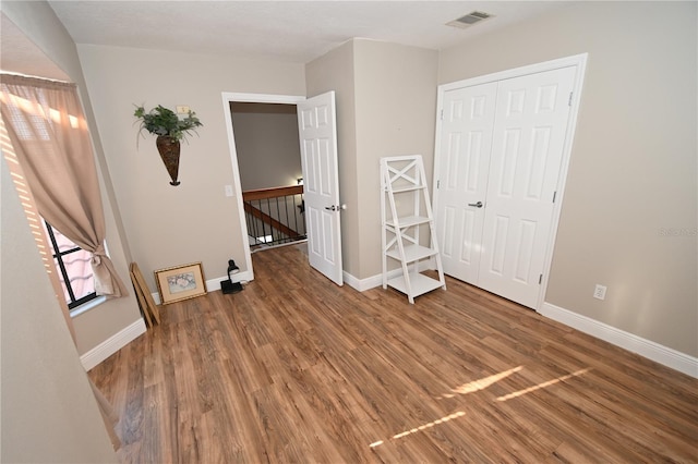 unfurnished bedroom featuring visible vents, baseboards, and wood finished floors