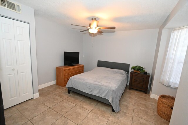 bedroom featuring visible vents, baseboards, ceiling fan, light tile patterned floors, and a closet