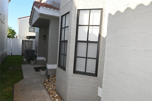 view of side of home with stucco siding, a tile roof, and fence