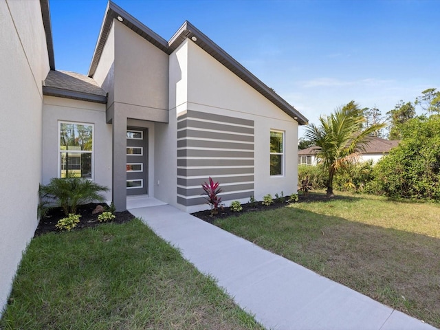 exterior space featuring a shingled roof, a front yard, and stucco siding