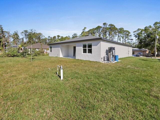 rear view of property with stucco siding and a yard