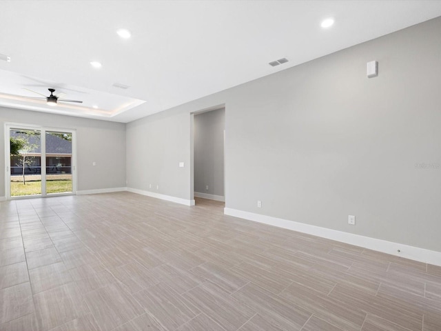 empty room featuring a tray ceiling, recessed lighting, a ceiling fan, and baseboards