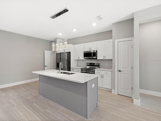 kitchen featuring tasteful backsplash, a center island with sink, visible vents, stainless steel appliances, and a sink