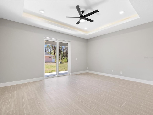 unfurnished room with a tray ceiling and baseboards