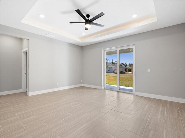 spare room with a tray ceiling, recessed lighting, visible vents, a ceiling fan, and baseboards