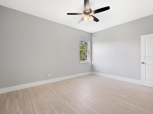 spare room featuring ceiling fan, light wood-style flooring, and baseboards