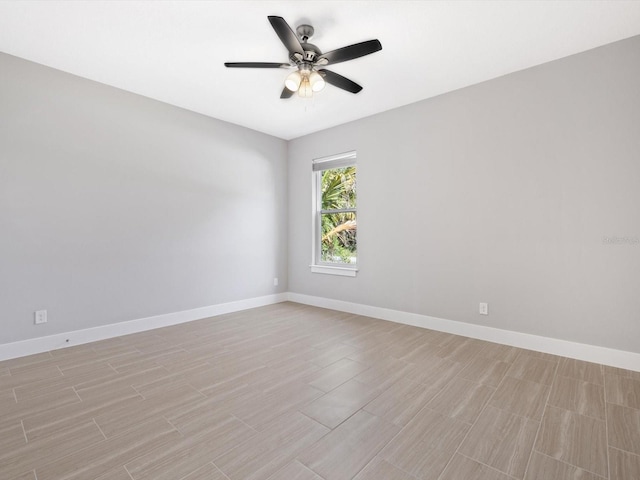 spare room featuring ceiling fan, light wood-type flooring, and baseboards