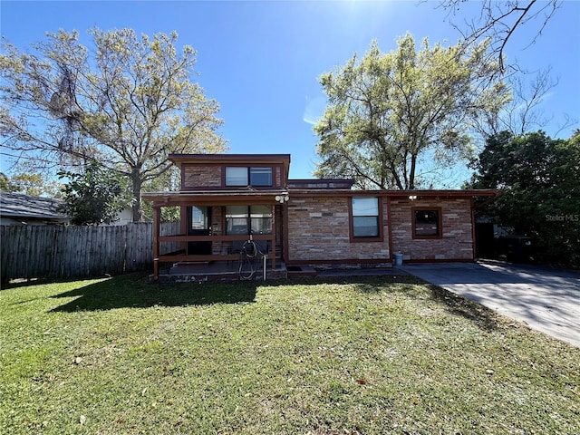 view of front of home with stone siding, fence, and a front lawn