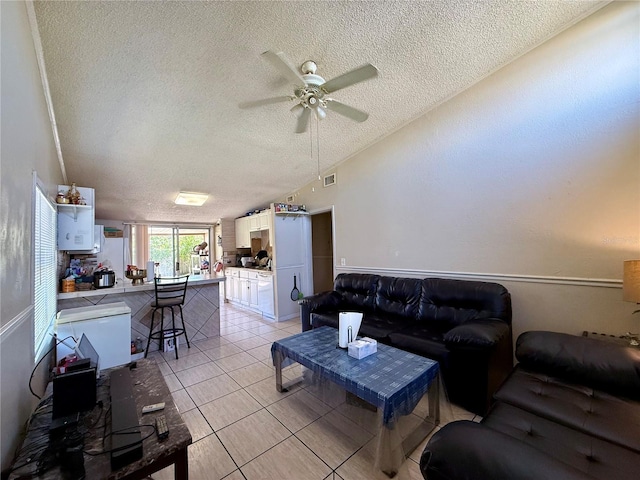 living area featuring visible vents, a ceiling fan, lofted ceiling, a textured ceiling, and light tile patterned flooring