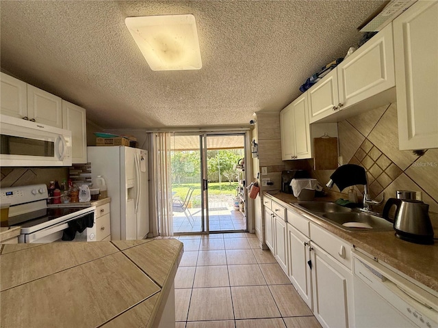 kitchen featuring white appliances, white cabinetry, decorative backsplash, and light tile patterned floors