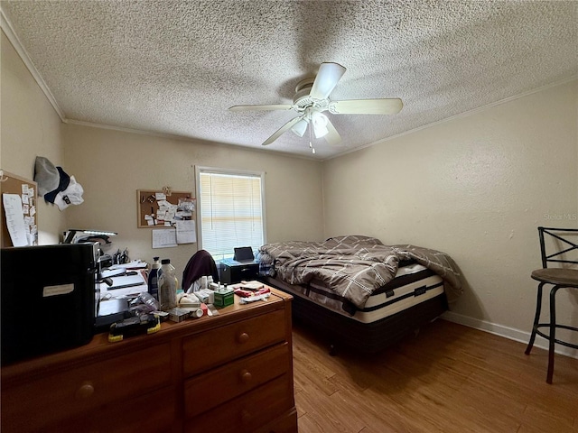 bedroom featuring a ceiling fan, a textured ceiling, ornamental molding, and wood finished floors