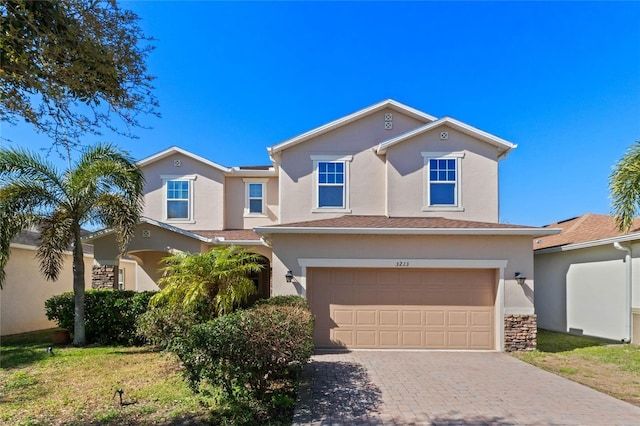 traditional-style home with decorative driveway, a garage, and stucco siding