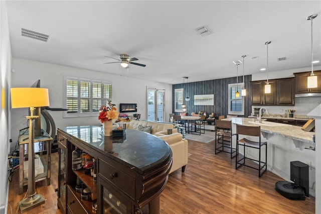 kitchen featuring dark wood-style floors, visible vents, dark brown cabinets, and an island with sink