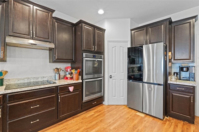 kitchen with dark brown cabinets, under cabinet range hood, light wood-type flooring, recessed lighting, and appliances with stainless steel finishes