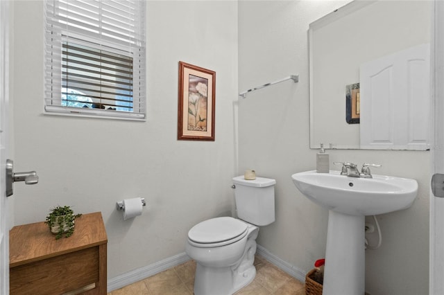 bathroom featuring tile patterned flooring, toilet, baseboards, and a sink