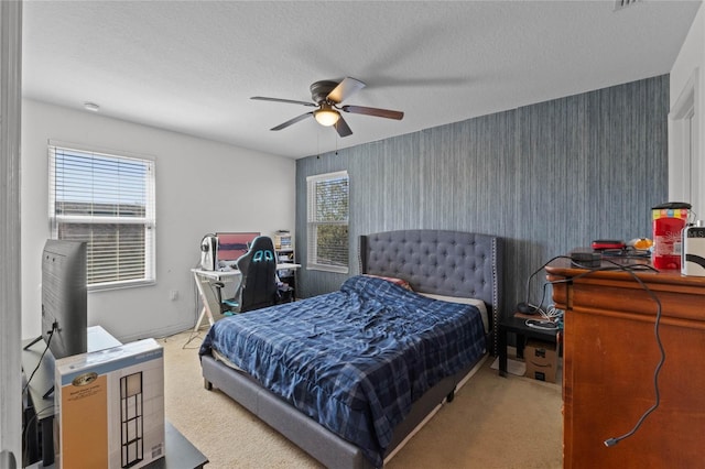 carpeted bedroom with multiple windows, a textured ceiling, ceiling fan, and wallpapered walls