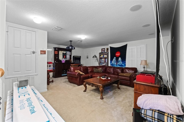 living area with visible vents, light colored carpet, and a textured ceiling