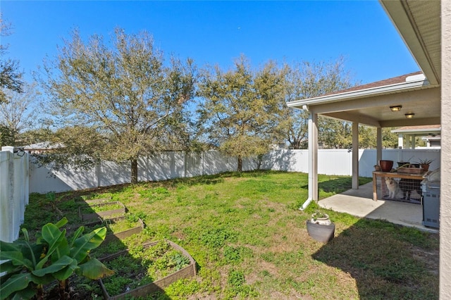 view of yard featuring a patio, a fenced backyard, and a garden