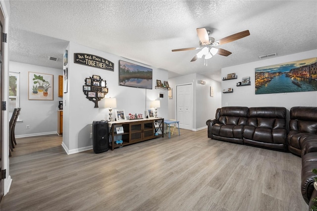 living room featuring visible vents, ceiling fan, and wood finished floors