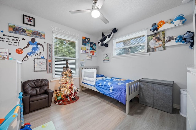 bedroom with ceiling fan, a textured ceiling, and wood finished floors