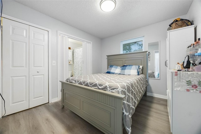 bedroom featuring a closet, a textured ceiling, baseboards, and wood finished floors